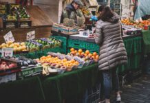 woman standing in front of assorted fruits displayed